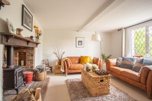 View of the lounge with the fireplace on the left a two seater sofa ahead and another to the right with the window behind