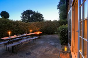 Image of the outdoor patio at twilight with the fire pit on and candles and food on the table