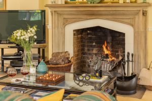 Image of a coffe table with accessories and the lit fireplace in the background