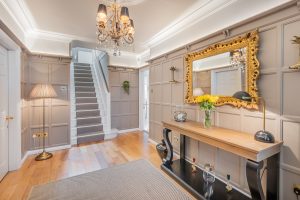 Image of an entrance hall with a mirror to the left and stairs in front