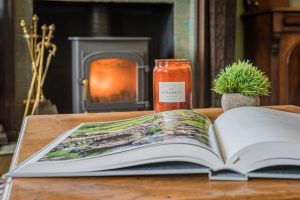 Image of a coffee table with an open book and a fireplace in the background