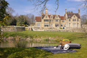 Image of the lake, manor house in the background and a picnic laid out.