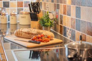 Image of a kitchen counter with a board with a loaf of bread and cherry tomatoes.