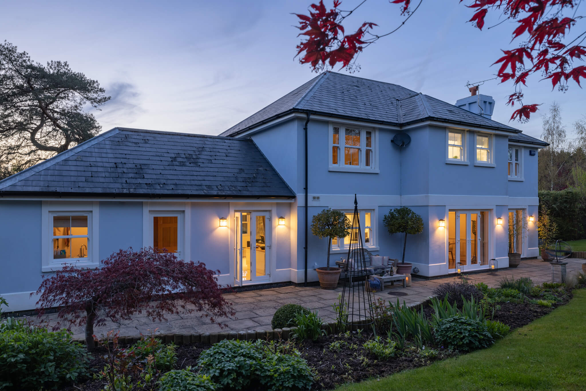 Twilight image of the rear of the home showcasing the garden and patio area