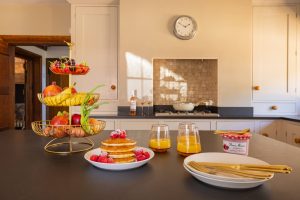 image of the kitchen island with breakfast served and a bowl of fruit and vegtables