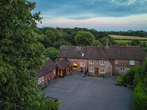 Twilight drone image of the front of the home including the driveway and views beyond the garden